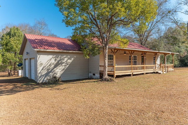 view of front of home with a garage, a front lawn, ceiling fan, and a porch