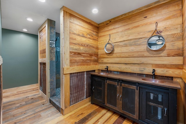 bar with sink, light hardwood / wood-style floors, and wooden counters