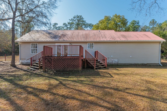 rear view of house featuring a deck and a lawn