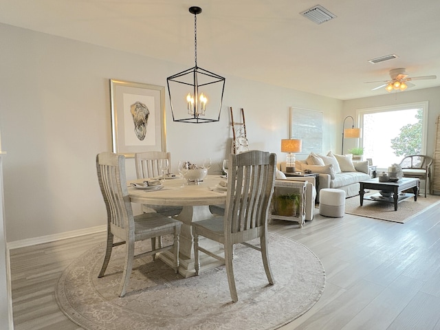 dining space featuring ceiling fan with notable chandelier and light wood-type flooring