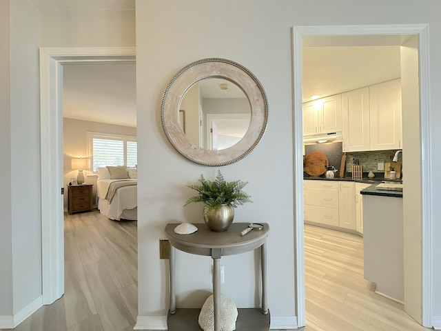 hallway with sink and light hardwood / wood-style flooring