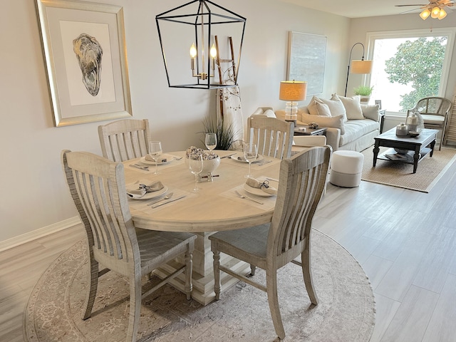 dining space with ceiling fan with notable chandelier and light hardwood / wood-style floors