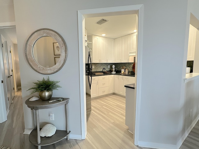 kitchen with white cabinetry, light wood-type flooring, and decorative backsplash