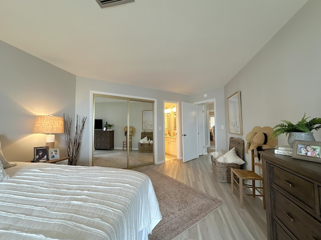 bedroom with ensuite bathroom, a closet, and light wood-type flooring