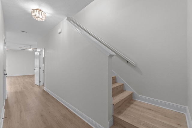 stairs featuring ceiling fan and wood-type flooring