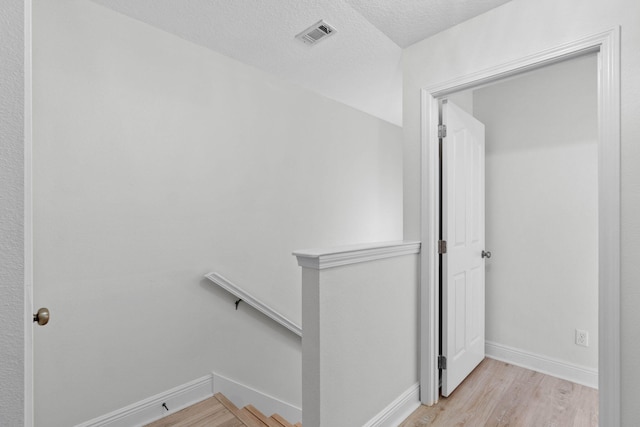 staircase with wood-type flooring and a textured ceiling