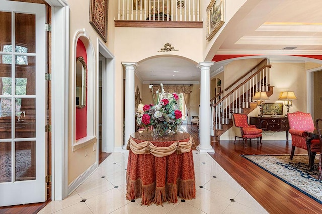 tiled foyer with a wealth of natural light, a high ceiling, decorative columns, and ornamental molding