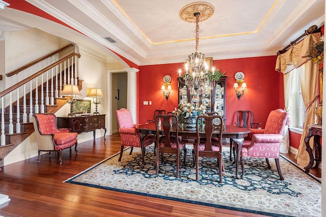 dining room featuring a tray ceiling, ornamental molding, decorative columns, and wood-type flooring