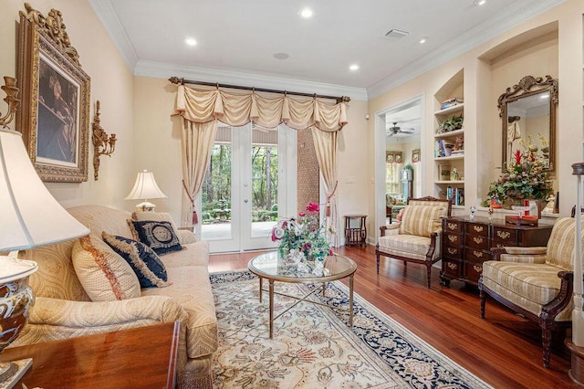 living room with crown molding, wood-type flooring, built in features, and ceiling fan