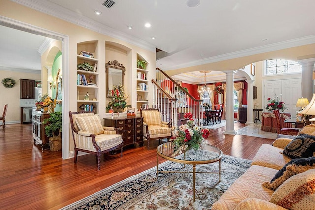 living room with ornamental molding, ornate columns, built in shelves, and wood-type flooring