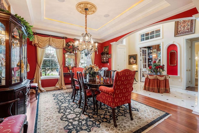 dining room featuring a raised ceiling, a chandelier, crown molding, and hardwood / wood-style floors