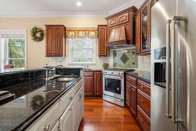 kitchen with custom exhaust hood, dark stone counters, crown molding, dark wood-type flooring, and stainless steel appliances