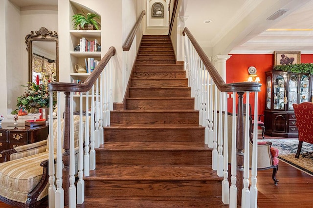 stairway with ornate columns, hardwood / wood-style flooring, and crown molding