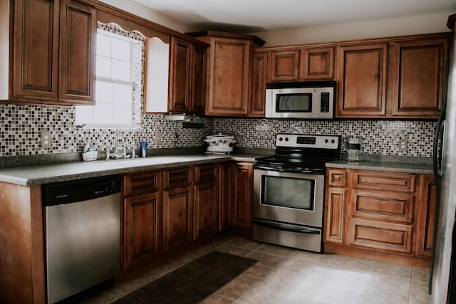 kitchen with tasteful backsplash, appliances with stainless steel finishes, and light tile patterned floors