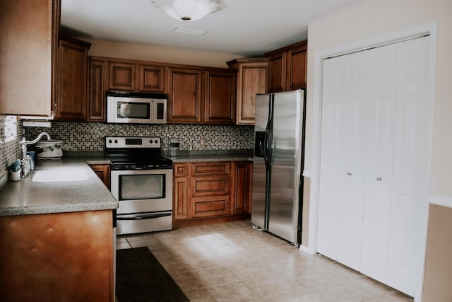 kitchen with appliances with stainless steel finishes, decorative backsplash, and light tile patterned floors