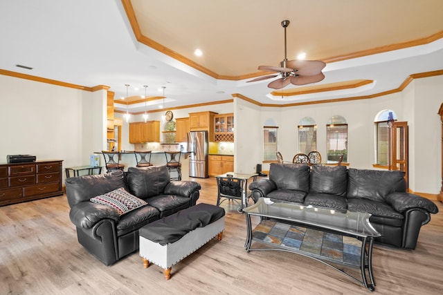 living room featuring ornamental molding, ceiling fan, light hardwood / wood-style floors, and a tray ceiling