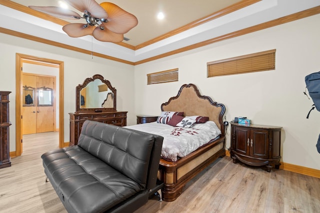 bedroom with ornamental molding, ceiling fan, light wood-type flooring, and a tray ceiling