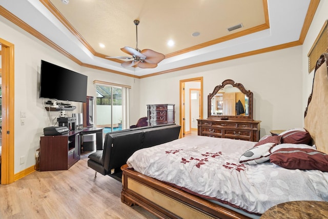 bedroom with ceiling fan, ornamental molding, a tray ceiling, and light wood-type flooring