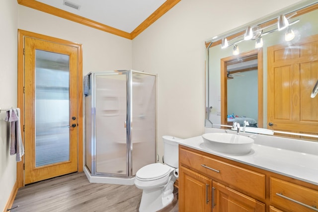 bathroom with crown molding, hardwood / wood-style flooring, vanity, a shower with shower door, and toilet