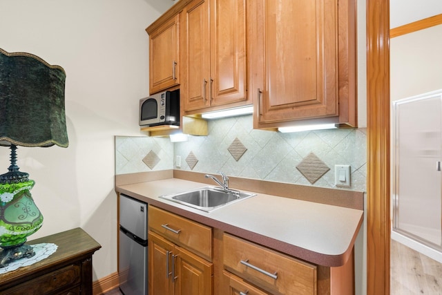 kitchen featuring appliances with stainless steel finishes, light hardwood / wood-style floors, sink, and decorative backsplash