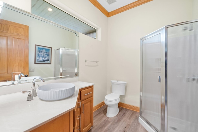 bathroom featuring hardwood / wood-style floors, vanity, ornamental molding, toilet, and walk in shower