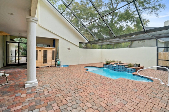 view of swimming pool featuring a patio, glass enclosure, and an in ground hot tub