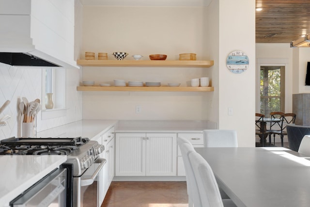 kitchen with tasteful backsplash, premium range hood, white cabinets, and appliances with stainless steel finishes