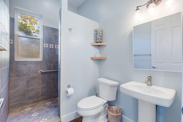 bathroom with a tile shower and toilet