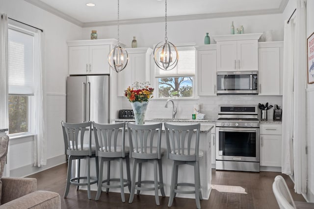 kitchen with stainless steel appliances, white cabinetry, hanging light fixtures, and light stone countertops