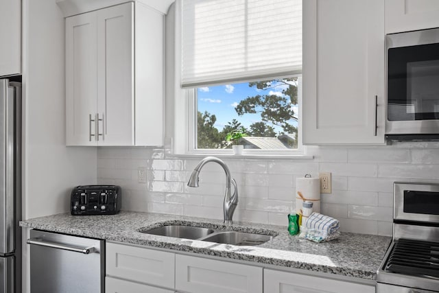 kitchen featuring sink, stainless steel appliances, white cabinets, and light stone countertops