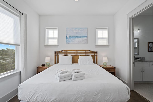 bedroom featuring ensuite bathroom and dark hardwood / wood-style floors