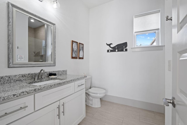 bathroom featuring vanity, a shower with door, and toilet