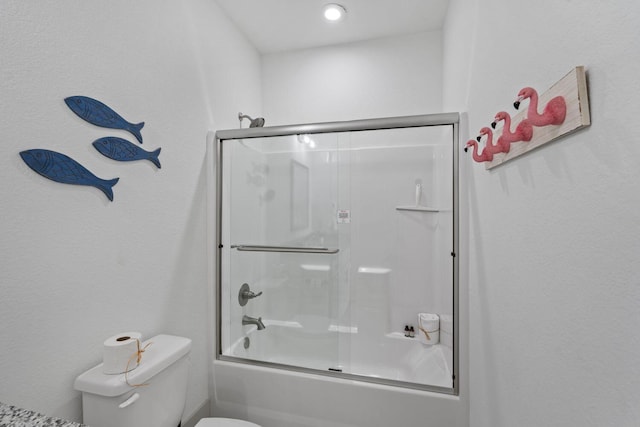 bathroom featuring toilet and bath / shower combo with glass door