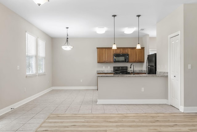 kitchen featuring pendant lighting, kitchen peninsula, sink, and black appliances