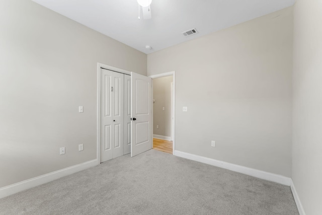 unfurnished bedroom featuring ceiling fan, a closet, and light carpet