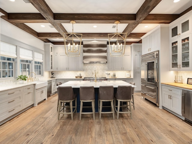 kitchen with built in refrigerator, sink, exhaust hood, and an inviting chandelier