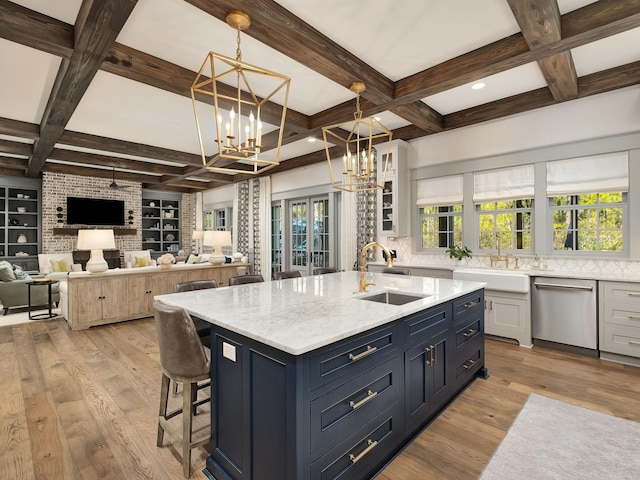 kitchen featuring sink, dishwasher, a kitchen island with sink, and hanging light fixtures