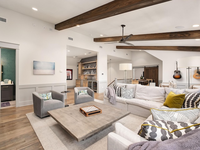 living room featuring wine cooler, bar, vaulted ceiling with beams, light hardwood / wood-style flooring, and ceiling fan