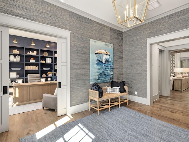 sitting room featuring hardwood / wood-style flooring, ornamental molding, and a chandelier