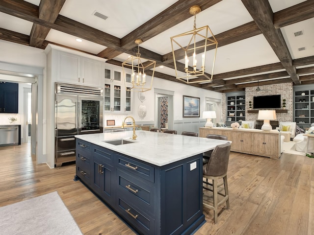 kitchen with sink, light hardwood / wood-style flooring, blue cabinetry, white cabinetry, and hanging light fixtures