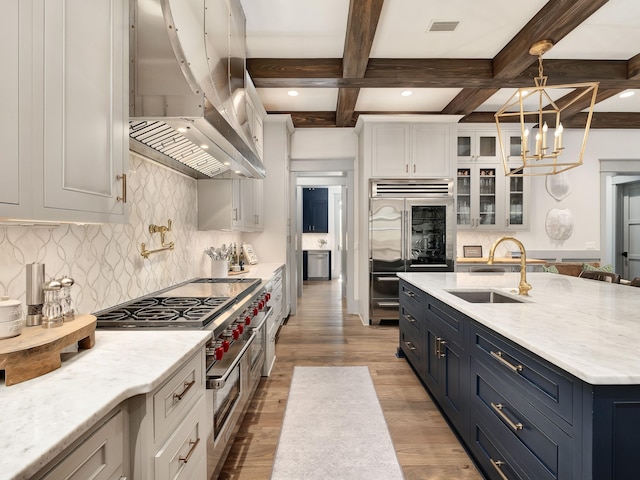 kitchen with white cabinetry, sink, decorative light fixtures, and extractor fan