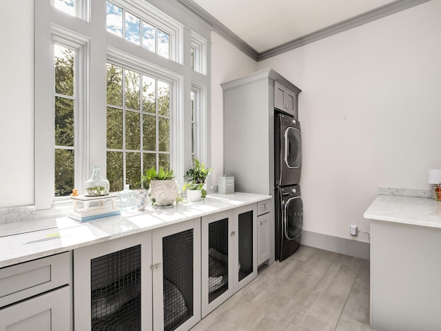 washroom with wine cooler, crown molding, cabinets, stacked washing maching and dryer, and light hardwood / wood-style floors