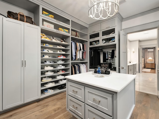 walk in closet with a chandelier and light hardwood / wood-style floors