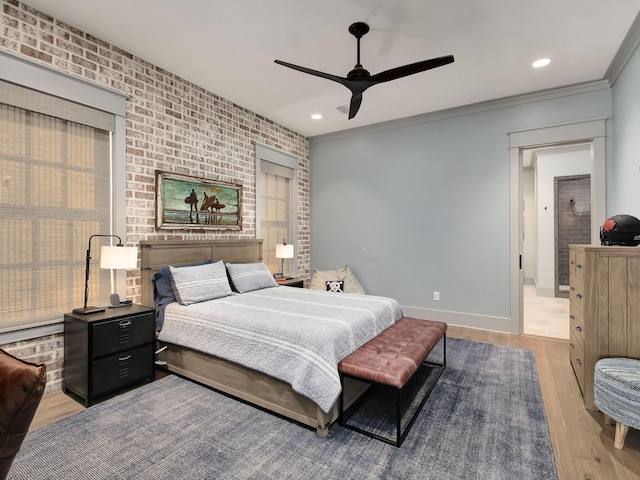 bedroom featuring light hardwood / wood-style flooring, ornamental molding, ceiling fan, and brick wall