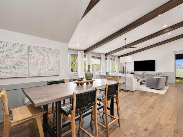 dining space featuring ceiling fan, vaulted ceiling with beams, and light wood-type flooring