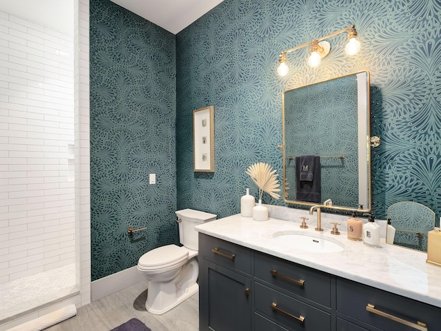 bathroom featuring vanity, tiled shower, and toilet