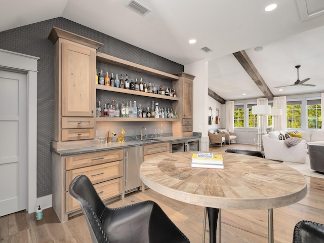 bar featuring light brown cabinetry, wood-type flooring, sink, vaulted ceiling with beams, and stainless steel dishwasher