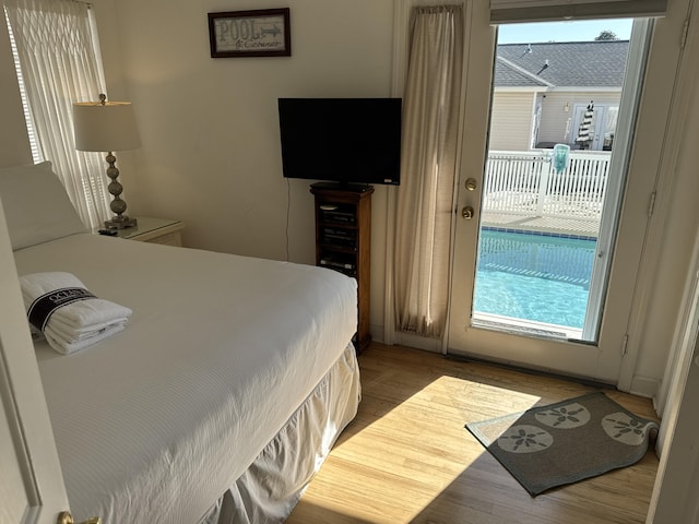 bedroom featuring multiple windows, access to outside, and light wood-type flooring