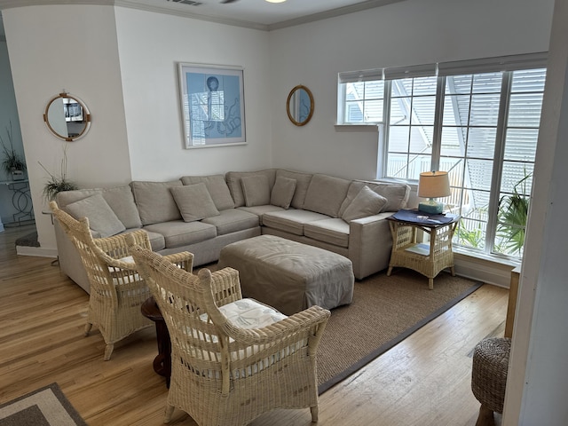 living room with ornamental molding, a healthy amount of sunlight, and light wood-type flooring