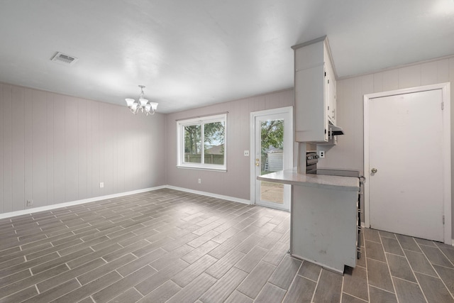 kitchen with a breakfast bar, white cabinetry, range, a notable chandelier, and pendant lighting